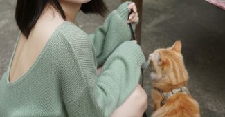 ChatGPT_AI提示词_一位年轻的亚洲女性在水泥露台上蹲着，向镜头投去含羞的微笑，并伸手向一只橙色虎斑猫_chatgpt会员版不能推理缩略图