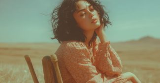 ChatGPT_AI提示词_一位20岁自然美女在草地上坐着，黑色波浪长发，沉思神情_开gpt会员缩略图