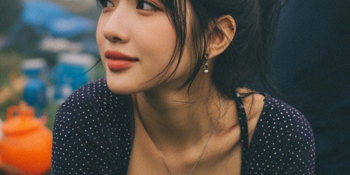 ChatGPT提示词_一位成年东亚女性在草地上坐着，穿着海军蓝亮点背心和高腰卡其裤，手里拿着一条白毛巾，神态自然_gpt会员代充缩略图