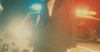 ChatGPT提示词_一位穿着黑色西装和裙子的摇滚风格女性自信地在夜晚的警车旁摆姿势_chatgpt会员有什么用缩略图