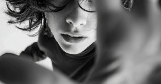 ChatGPT提示词_一个人的上半身出现在广角高角度镜头中，双臂向摄像机展开，手靠近镜头，产生透视效果，头部转动，发丝飞舞，眼神与摄像机紧密对视缩略图