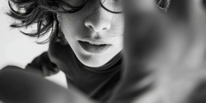 ChatGPT提示词_一个人的上半身出现在广角高角度镜头中，双臂向摄像机展开，手靠近镜头，产生透视效果，头部转动，发丝飞舞，眼神与摄像机紧密对视缩略图