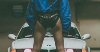 AI提示词_一位长发黑衣女性自信地站在地下停车场，身后是一辆白色BMW E36 M3_chatgpt会员激活码缩略图