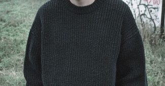 AI提示词_一位年轻瘦男士穿着宽松深灰色针织毛衣和深蓝色牛仔裤，目光坚定但略显疲惫，站在雾气笼罩的田野中_chatgpt5缩略图