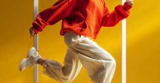 ChatGPT提示词_一名穿着红色连帽衫和奶油色长裤的女性充满活力地走出框架_gpt会员充值缩略图