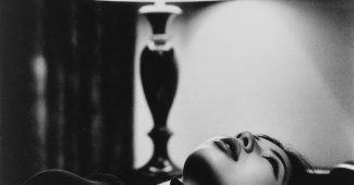 ChatGPT提示词_一位27岁的日本女性在现代酒店房间的床上侧卧，穿着黑色高领上衣，目光专注于一盏灯_chat gpt会员共享缩略图