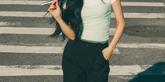 ChatGPT提示词_一位年轻的韩国女性正在自信地涂抹唇彩，穿着白色短袖T恤和薄纱薄绿背心，搭配黑色宽腿裤，展现出强烈的轮廓感_gpt会员多少钱缩略图