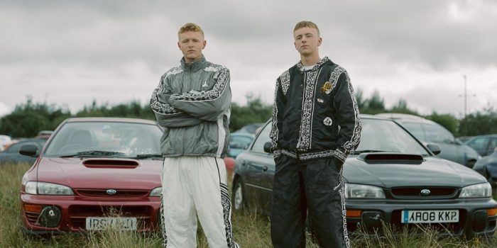 ChatGPT提示词_两位穿着带有传统爱尔兰花纹运动服的爱尔兰男子，站在贝尔法斯特郊外的田野里，身后是他们的斯巴鲁汽车_国内如何买gpt会员卡便宜点缩略图